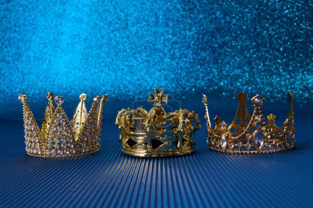 Día de la Epifanía o concepto de Día de Reyes Magos. Tres coronas de oro sobre fondo azul brillante.