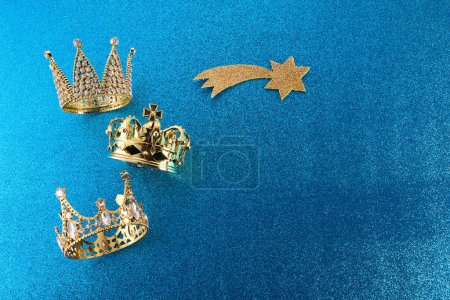 Epiphany Day or Dia de Reyes Magos concept. Three gold crowns on blue sparkling background.