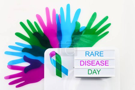 Rare Disease Day Background. Colorful hands and ribbon on white background.