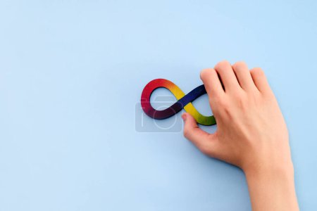 Autistische Jungenhände und Regenbogen-Acht-Unendlichkeitssymbol. Tag des Autismus-Bewusstseins