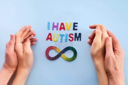 Autistische Jungen und Vater Hände mit Regenbogen acht Unendlichkeit Symbol. Tag des Autismus-Bewusstseins