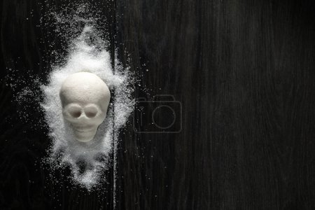 Un montículo de azúcar en forma de cráneo en una superficie de madera que simboliza el concepto de dieta poco saludable.