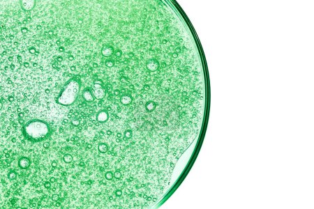 Gros plan d'un comprimé effervescent vert bouillonnant dans l'eau, montrant des pétillements et des bulles.