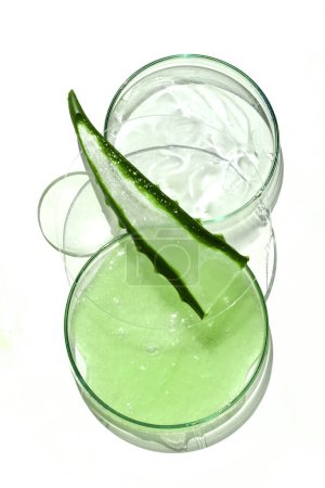 Open container with fresh aloe vera gel and aloe leaf on a clean, bright background.