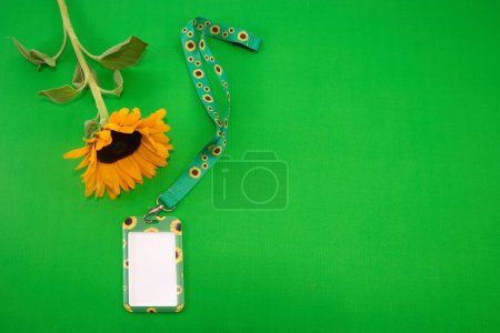 Sonnenblumen-Schlüsselband, Symbol für Menschen mit unsichtbaren oder versteckten Behinderungen.. Eine lebendige Sonnenblume und ein Schlüsselband vor leuchtend grünem Hintergrund.