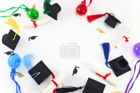 Top view of graduation caps, diplomas, and colorful tassels on white background.