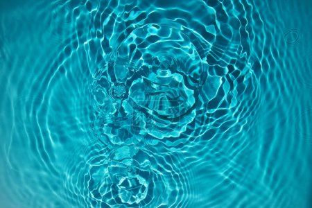 Abstract view of turquoise water with concentric ripples and light refractions.