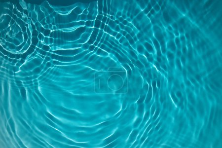 Abstract view of turquoise water with concentric ripples and light refractions.