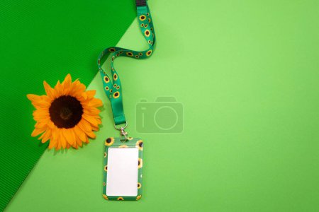 Photo for Sunflower lanyard, symbol of people with invisible or hidden disabilities.. A vibrant sunflower and a lanyard badge against a bright green backdrop. - Royalty Free Image