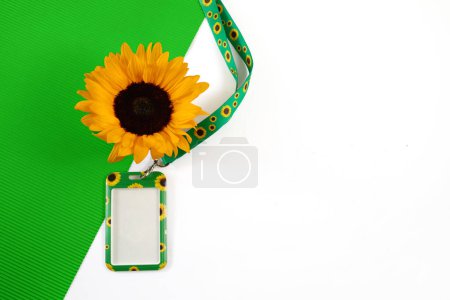 Sonnenblumen-Schlüsselband, Symbol für Menschen mit unsichtbaren oder versteckten Behinderungen.. Eine lebendige Sonnenblume und ein Schlüsselband vor leuchtend grünem Hintergrund.