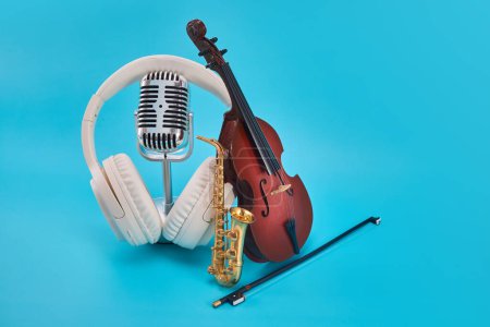 Eine Geige mit Bogen, Saxophon, Kopfhörer und Mikrofon auf blauem Hintergrund.