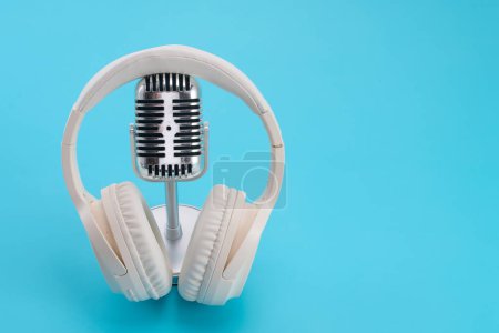 A retro microphone with white headphones against a blue background.