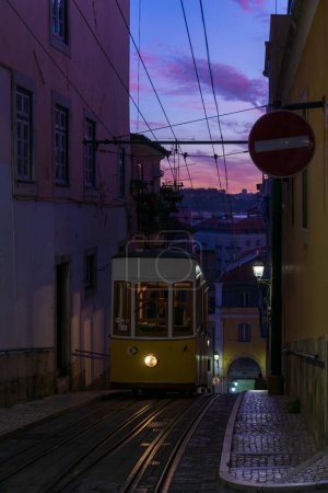 Foto de Antique yellow cable car on a narrow Portuguese street at sunset cityscape - Imagen libre de derechos