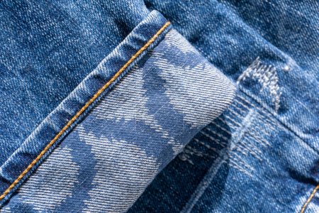 Blue Jeans mit Mustern an den Manschetten und dekorativen Nähten Hintergrund Nahaufnahme