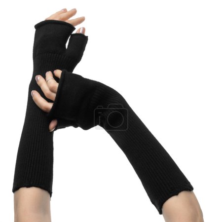 Foto de Elegantes manos femeninas en largos guantes negros sin dedos de lana con manoplas sobre un fondo blanco de cerca - Imagen libre de derechos