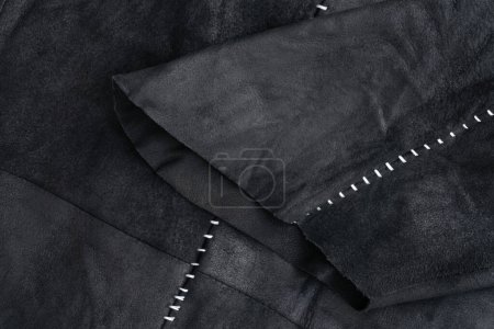 Detail of a black suede jacket with white contrast stitching background close up