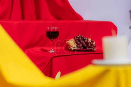 Foto de Copa de vino, pan y uvas sobre tela roja en luz dura. Simbolismo de la última cena de Cristo Jesús - Imagen libre de derechos