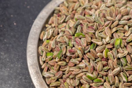 Whole pistachios on a traditional plate, concept shot and top view