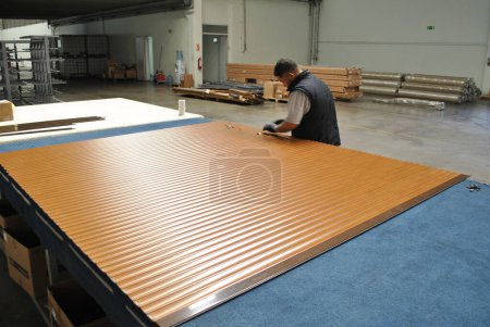 Photo for Factory produced shutter slats, polyurethane filled aluminum shutter, working worker - Royalty Free Image