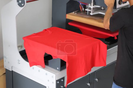 Photo for Press printing on colored t-shirts, press for printing images on fabric. Large industrial textile printing machine, when printing textiles for male workers - Royalty Free Image