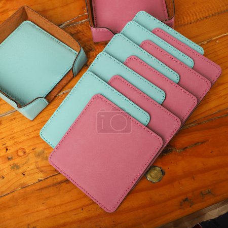 Photo for Leather table mats in teal and pink colors. Concept shot, top view. Custom background view of leather table coaster. Stitched and leather table coaster - Royalty Free Image