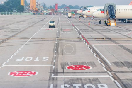 Photo for Ho Chi Minh City, Vietnam - October 2, 2019: Stop sign on the road near the aircraft parking at the airport. - Royalty Free Image