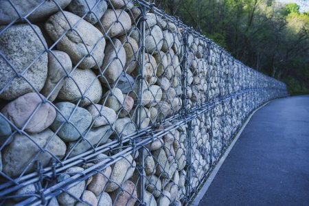 Valla de piedra con barras de hierro cerca de la acera. Diseño en el parque