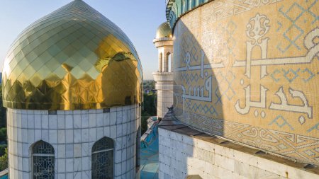 Foto de Almaty, Kazajstán - 17 de agosto de 2023: Oración en la pared de la cúpula cerca del minarete. Mosaico árabe - Imagen libre de derechos