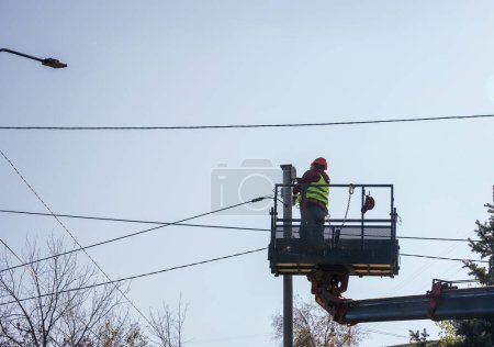 Foto de Almaty, Kazajstán - 17 de agosto de 2023: Un trabajador en una torre telescópica repara una cámara CCTV. - Imagen libre de derechos