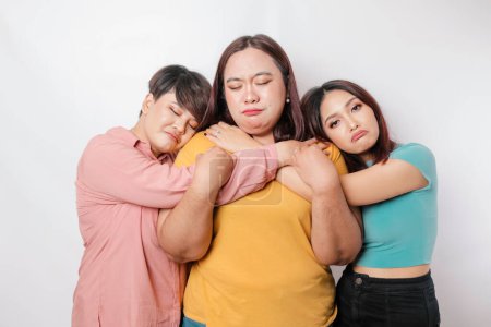 Téléchargez les photos : Un portrait de trois amis à l'air triste pleurant essuya ses larmes et se serra dans ses bras, fond blanc isolé - en image libre de droit