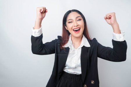 Eine junge asiatische Geschäftsfrau mit glücklichem, erfolgreichen Gesichtsausdruck trägt einen schwarzen Anzug, der von weißem Hintergrund isoliert ist