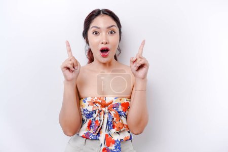 Photo for Attractive Asian woman look shocked while pointing up to copy space ad new isolated over white background - Royalty Free Image