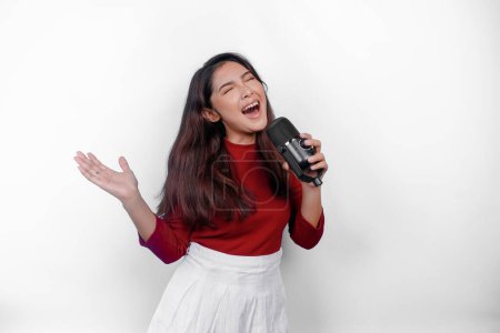 Photo for Portrait of carefree Asian woman, having fun karaoke, singing in microphone while standing over white background - Royalty Free Image