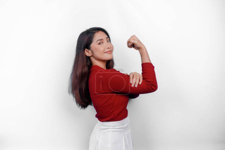 Photo for Excited Asian woman wearing a red top showing strong gesture by lifting her arms and muscles smiling proudly - Royalty Free Image