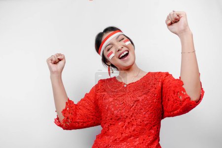 Photo for A young Asian woman with a happy successful expression wearing red kebaya and headband isolated by white background. Indonesia's independence day concept. - Royalty Free Image