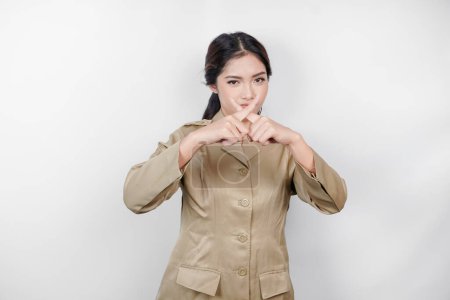 Téléchargez les photos : Jeune femme asiatique portant un uniforme marron montre les mains croisées ou geste d'arrêt, fond blanc isolé - en image libre de droit