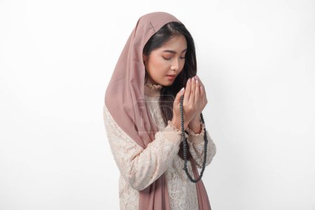Schöne asiatische Muslimin, die inbrünstig zu Gott betet, mit erhobenen Händen betet und Gebetsperlen hält. Ramadan und Eid Mubarak-Konzept