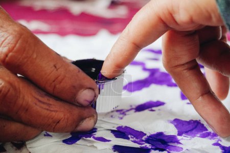 Primer retrato del dedo meñique sumergiéndose en tinta púrpura después de votar por el presidente de Indonesia y las elecciones gubernamentales 2024