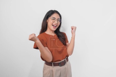 Photo for A young Asian woman wearing brown shirt and eyeglasses with a happy successful expression isolated by white background. - Royalty Free Image