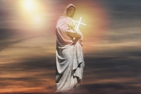Téléchargez les photos : Vierge Marie statue sainte fantasmée avec crucifix et ciel dramatique. - en image libre de droit