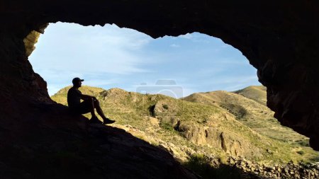 Foto de Imagen borrosa con una silueta de un hombre en el borde de una cueva en un viaje por la naturaleza. Silueta de enfoque suave del hombre en una cueva en viaje en la naturaleza. - Imagen libre de derechos