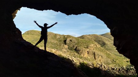 Foto de Imagen borrosa con una silueta de una mujer en el borde de una cueva en un viaje por la naturaleza. Silueta de enfoque suave de la mujer en una cueva en viaje en la naturaleza. - Imagen libre de derechos