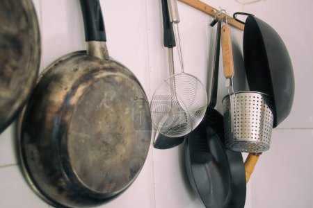 Foto de Detalle de foco suave de sartenes y utensilios de cocina sentados en la pared de la cocina - Imagen libre de derechos
