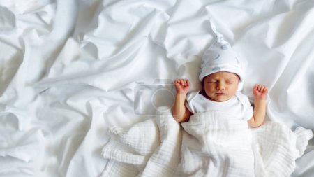 Téléchargez les photos : Un nouveau-né en chapeau blanc, dort doucement sur un fond blanc avec une place pour le texte - en image libre de droit