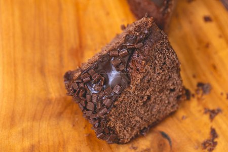 Photo for Chocolate cake with creamy chocolate sauce and decorated with chocolate sprinkles on a wooden board. Slice of cake. - Royalty Free Image