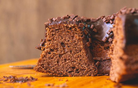 Photo for Chocolate cake with creamy chocolate sauce and decorated with chocolate sprinkles on a wooden board. - Royalty Free Image