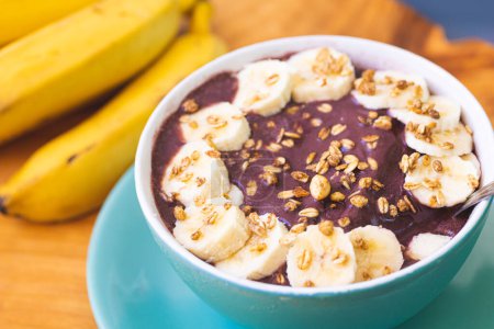 Photo for Frozen acai with banana, condensed milk and granola served in a green bowl on a wooden board. Close-up photo. Brazilian food, dessert. - Royalty Free Image