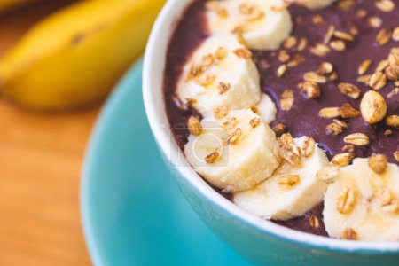 Photo for Frozen acai with banana, condensed milk and granola served in a green bowl on a wooden board. Close-up photo. Brazilian food, dessert. - Royalty Free Image