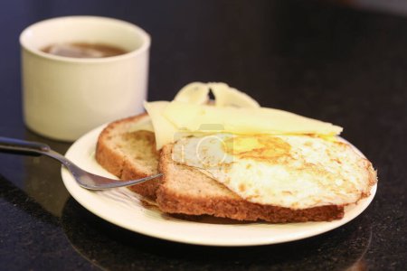Foto de Vista de cerca de tostadas con mantequilla y huevos fritos y taza de té en la mesa - Imagen libre de derechos