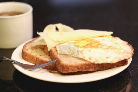 Photo for Close-up view of toasts with butter and fried eggs and cup of tea on table - Royalty Free Image